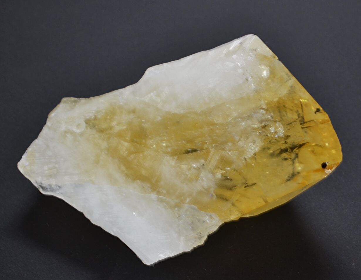 A piece of yellow quartz on a black surface.